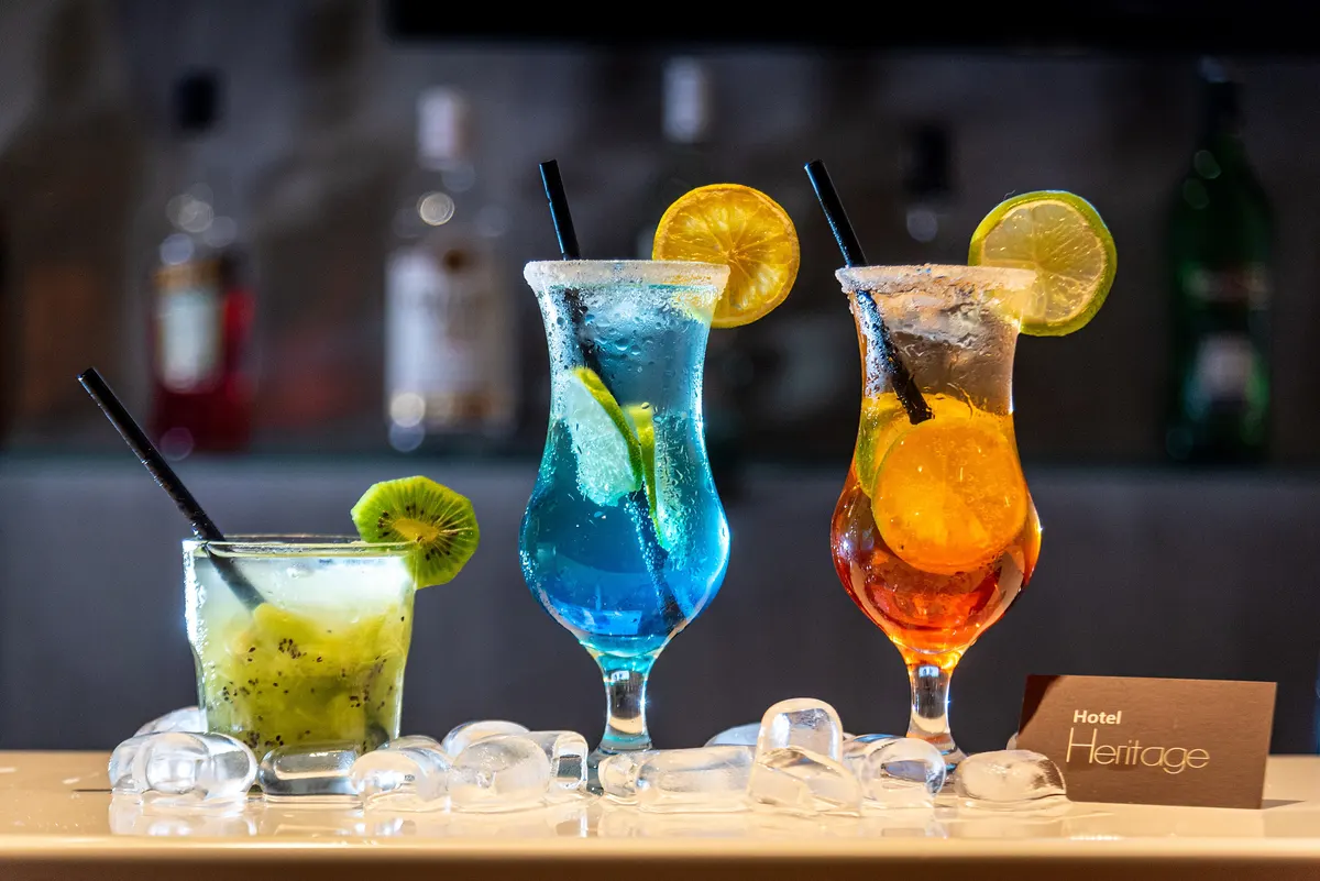 Três coquetéis coloridos sobre o balcão do bar do Hotel Heritage
