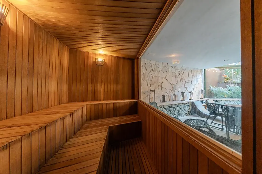 Sauna revestida em madeira, com janela para a área da piscina